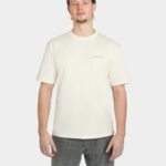 Model wearing the Uncaged Birds Tee in Off-White, front view with subtle “LAST BUCKS” chest print