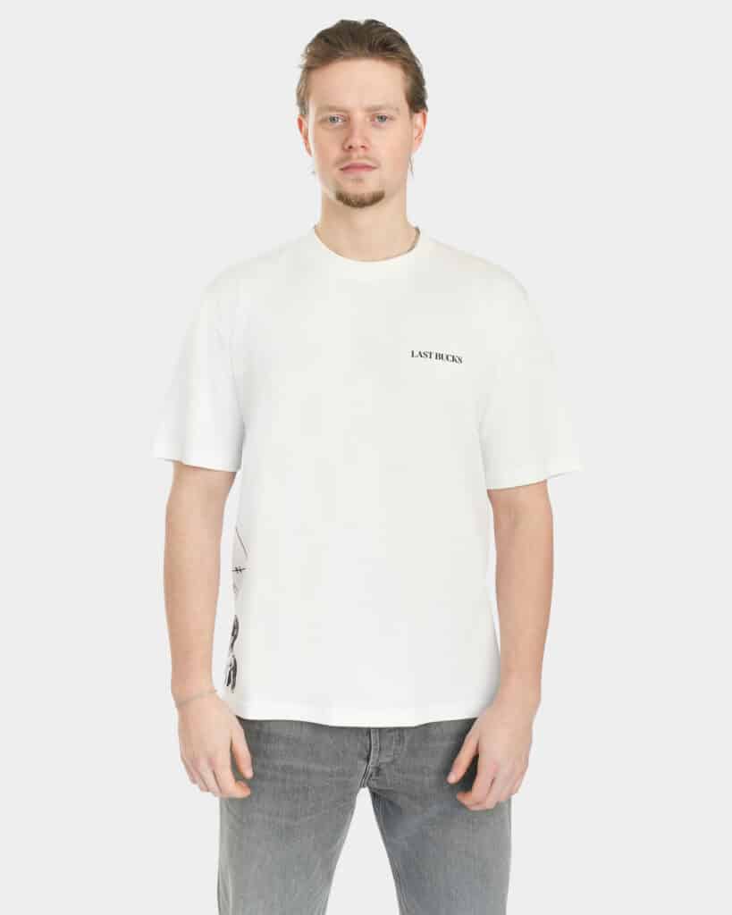 Male model wearing The Balance Side Tee in white, front view, with a small “LAST BUCKS” chest logo and a clean oversized fit