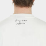 Close-up back neck detail of The Balance Side Tee in white on a male model, showing the small “Unregulated Apparel” script print below the collar