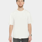 Male model wearing the Own The Sky Tee in White, front view, with a subtle tonal Last Bucks chest logo and a relaxed fit