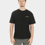 Male model wearing the Script Tee in Jet Black, front view, with a small gold “Last Bucks” chest logo on the left side