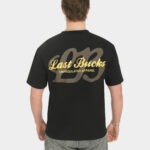Male model wearing the Script Tee in Jet Black, back view, featuring a large gold “Last Bucks” script print with “Unregulated Apparel” and a big “LB” graphic