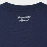 Close-up of the knitted "Unregulated Apparel" logo at the back neck on The Signature Sweater in Navy