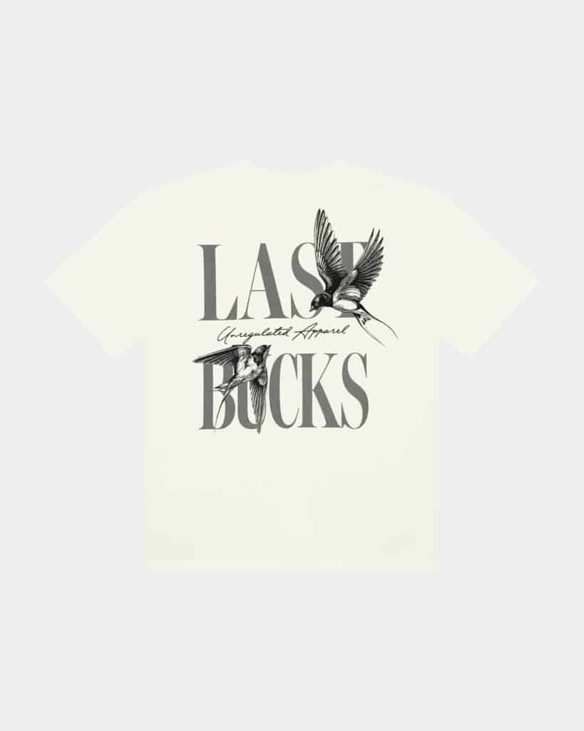 Uncaged Birds Tee Off-White - back view with large LAST BUCKS graphic, “Unregulated Apparel” script, and flying bird illustration