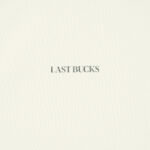 Uncaged Birds Tee in Off-White, front detail showing small “LAST BUCKS” print on the chest