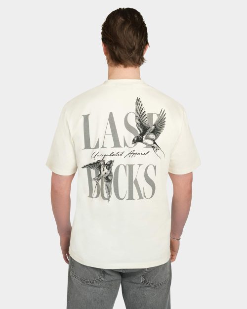 Model wearing the Uncaged Birds Tee in Off-White, back view with large “LAST BUCKS” graphic and flying birds artwork