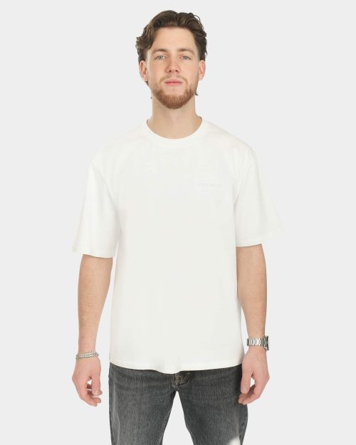 Male model wearing the Own The Sky Tee in White, front view, with a subtle tonal Last Bucks chest logo and a relaxed fit