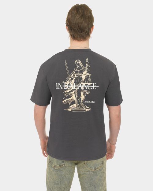 Male model wearing the In Balance Tee in Anthracite from the back, featuring a large IN BALANCE Lady Justice artwork and LAST BUCKS branding
