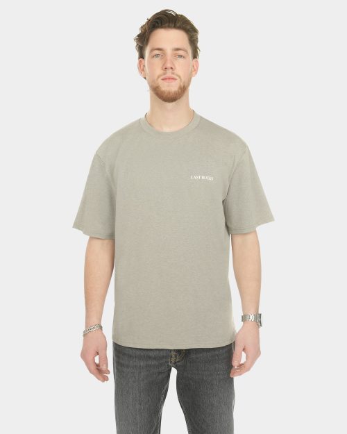 Male model wearing The Capital Tee in Mari Grey, front view, with a small “LAST BUCKS” chest logo