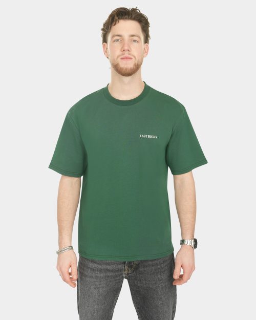 Male model wearing The Capital Tee in Hunter Green with a small “LAST BUCKS” chest logo
